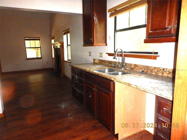 kitchen featuring dark hardwood / wood-style flooring, light stone counters, and sink