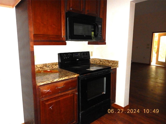 kitchen with dark hardwood / wood-style flooring, black appliances, and stone countertops