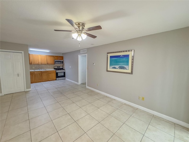 kitchen featuring stainless steel appliances, ceiling fan, and light tile patterned flooring