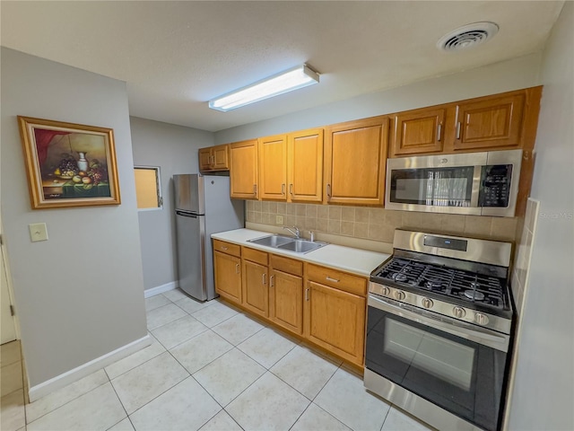 kitchen featuring tasteful backsplash, sink, light tile patterned floors, and appliances with stainless steel finishes