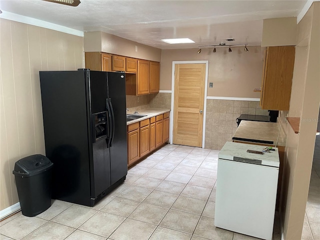 kitchen with sink, rail lighting, crown molding, light tile patterned flooring, and black refrigerator with ice dispenser