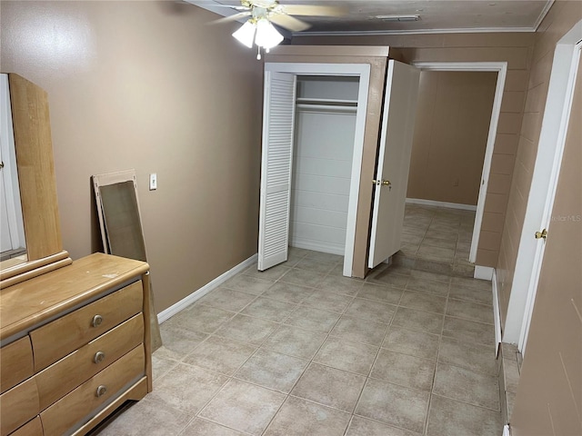 unfurnished bedroom with ornamental molding, a closet, light tile patterned floors, and ceiling fan