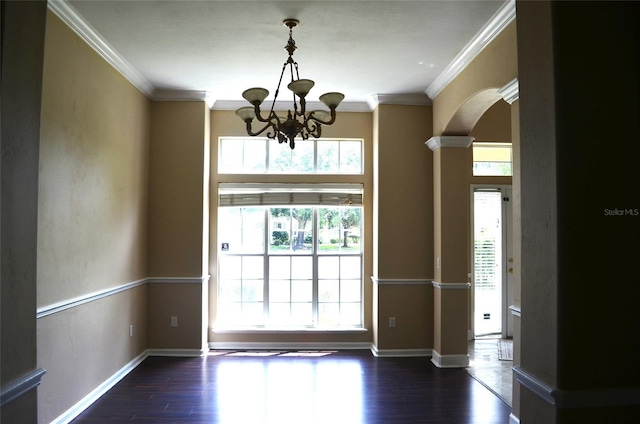 spare room featuring ornamental molding, ornate columns, an inviting chandelier, and dark hardwood / wood-style floors