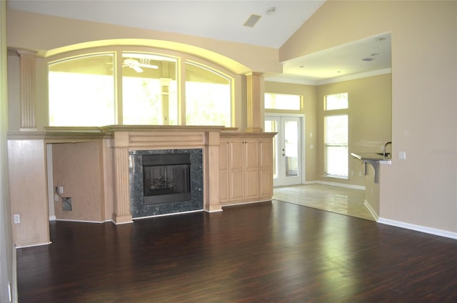 unfurnished living room with dark tile patterned floors, crown molding, decorative columns, a fireplace, and vaulted ceiling