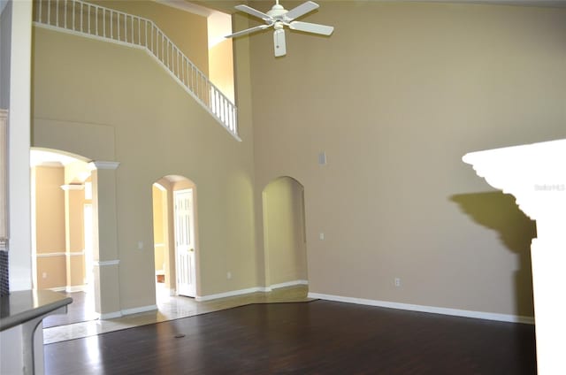 spare room featuring a towering ceiling, wood-type flooring, and ceiling fan