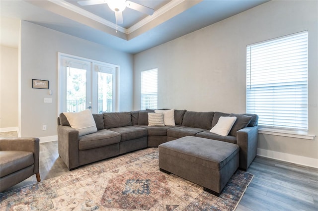 living room featuring ceiling fan, french doors, dark wood-type flooring, a raised ceiling, and crown molding