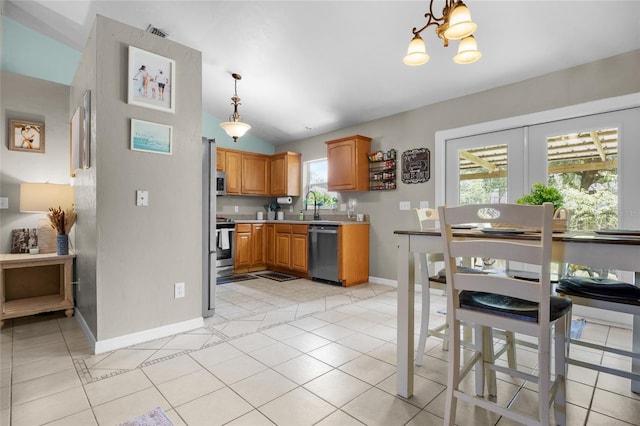 kitchen featuring stainless steel appliances, a healthy amount of sunlight, vaulted ceiling, and light tile patterned floors