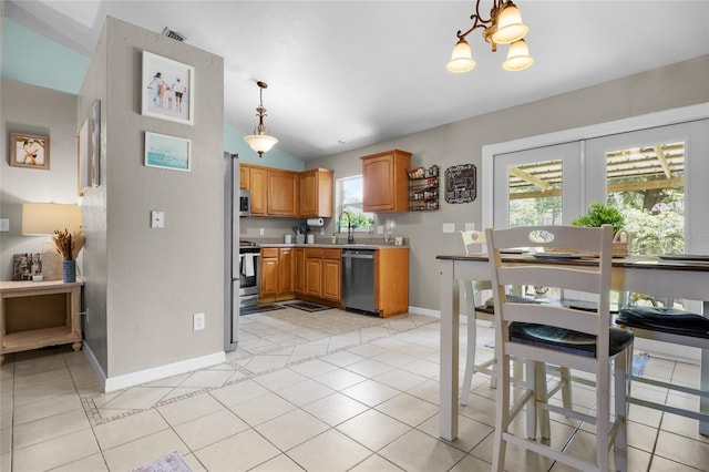 kitchen with light tile patterned flooring, appliances with stainless steel finishes, sink, and hanging light fixtures