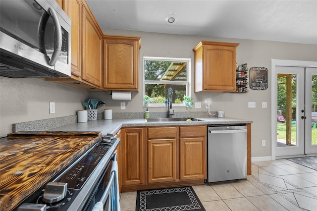 kitchen featuring light tile patterned floors, appliances with stainless steel finishes, sink, and plenty of natural light