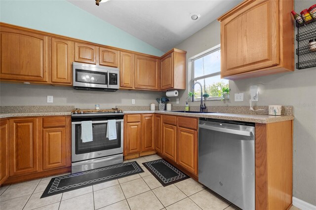 kitchen with light tile patterned floors, vaulted ceiling, appliances with stainless steel finishes, and sink