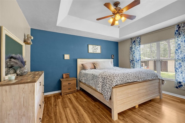 bedroom featuring wood-type flooring, a raised ceiling, and ceiling fan