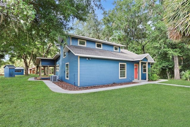 view of front property with a storage unit, a front yard, and central AC unit