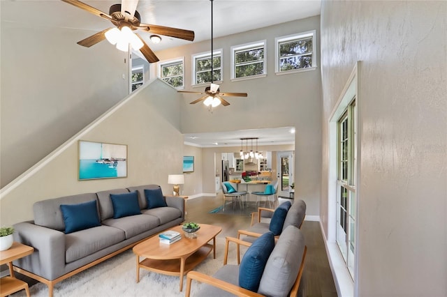 living room with ceiling fan, hardwood / wood-style floors, and a towering ceiling