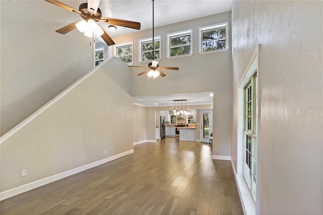 unfurnished living room with a high ceiling, ceiling fan, and dark hardwood / wood-style flooring