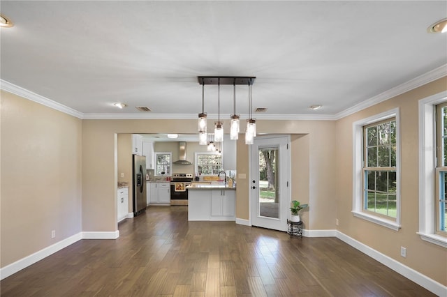 kitchen with white cabinets, wall chimney exhaust hood, a wealth of natural light, hanging light fixtures, and appliances with stainless steel finishes