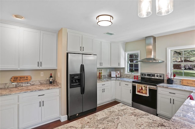 kitchen featuring white cabinets, dark wood-type flooring, decorative light fixtures, wall chimney exhaust hood, and appliances with stainless steel finishes