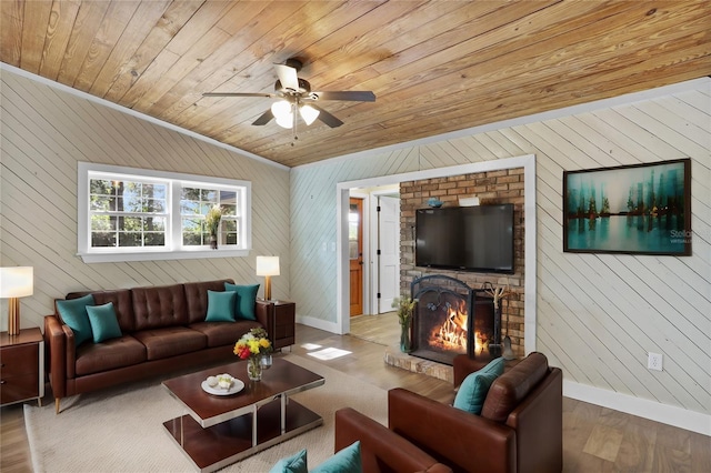 living room featuring light wood-type flooring, ceiling fan, a brick fireplace, wood walls, and wood ceiling