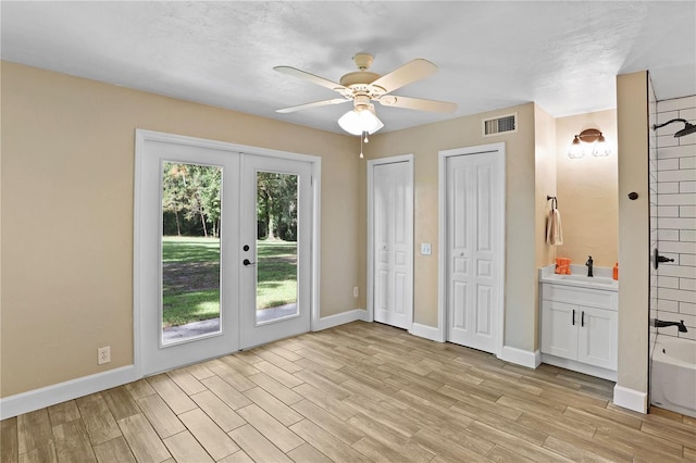 unfurnished bedroom featuring multiple closets, french doors, light hardwood / wood-style floors, ceiling fan, and access to exterior