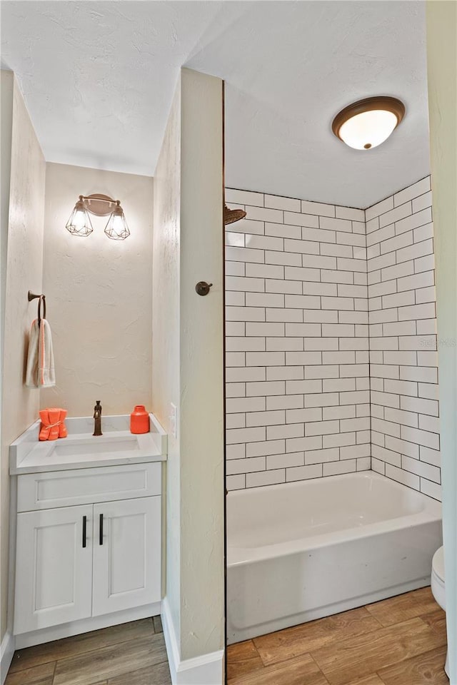 full bathroom with wood-type flooring, toilet, vanity, and tiled shower / bath