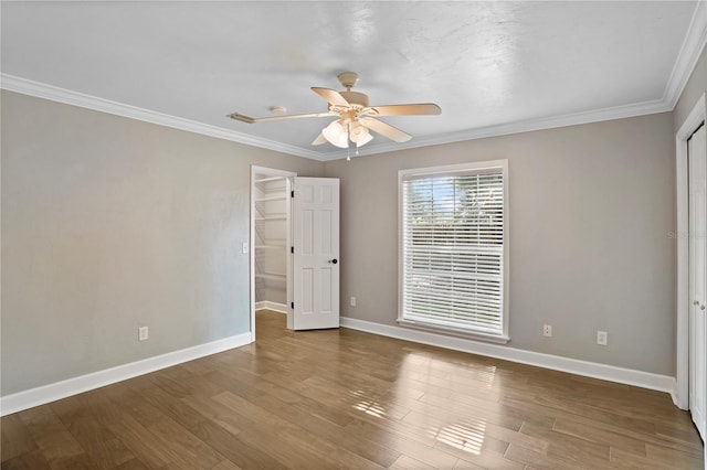 unfurnished bedroom with ceiling fan, ornamental molding, a closet, and hardwood / wood-style flooring