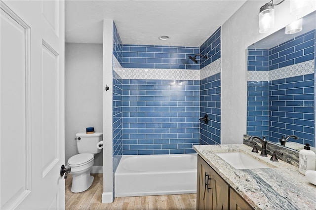 full bathroom featuring toilet, tiled shower / bath, wood-type flooring, and vanity