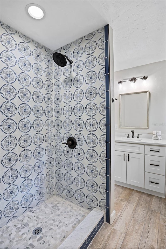 bathroom with a tile shower, wood-type flooring, and vanity