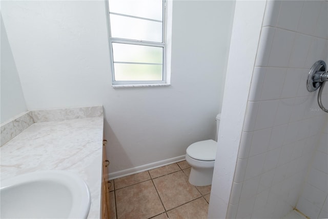 bathroom featuring tile patterned flooring, vanity, a tile shower, and toilet