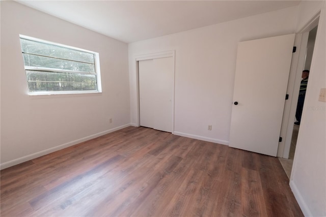 unfurnished bedroom with dark hardwood / wood-style flooring and a closet