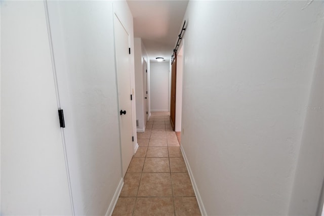 hallway featuring a barn door and light tile patterned floors