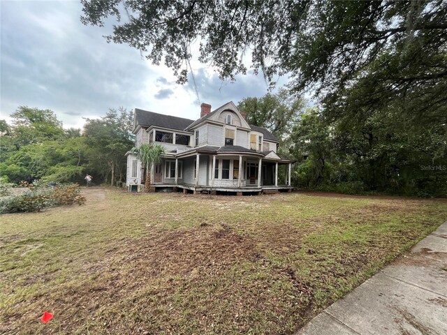 rear view of house featuring a porch and a yard