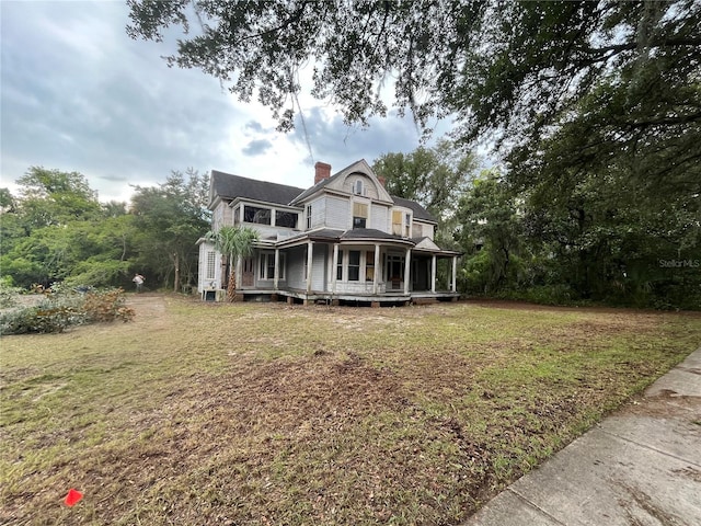 rear view of house featuring a porch and a yard