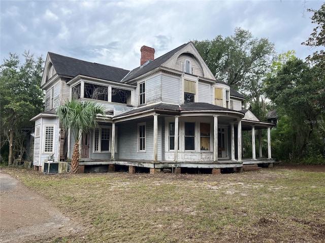 view of front of home with covered porch, a front yard, and central AC unit