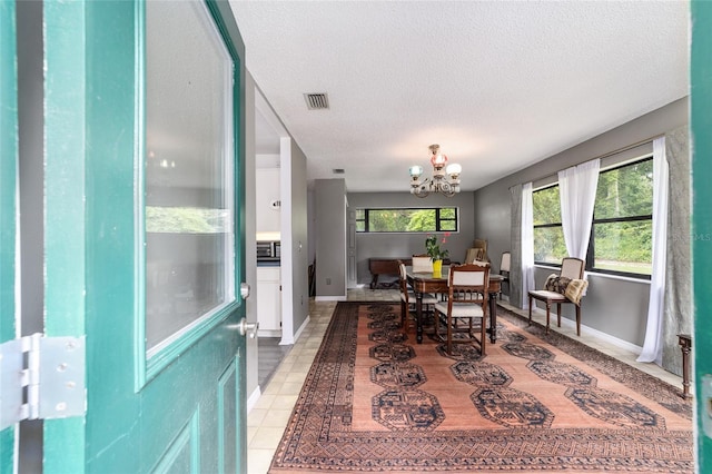 dining space featuring a textured ceiling, a notable chandelier, and light tile patterned flooring