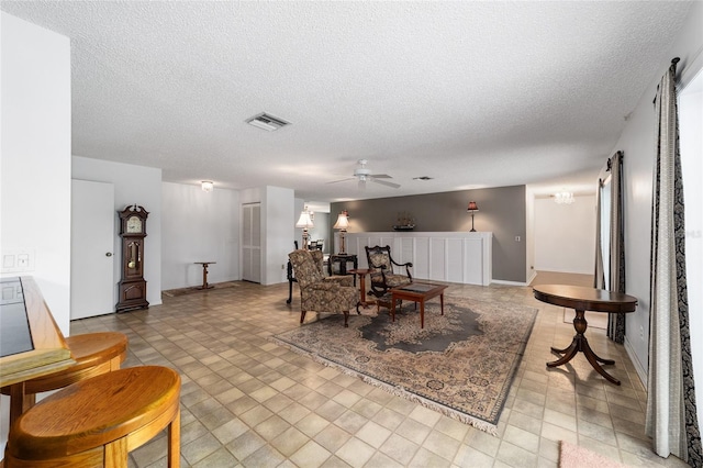 living room with ceiling fan and a textured ceiling