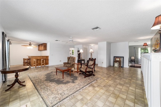 living room with ceiling fan and a textured ceiling