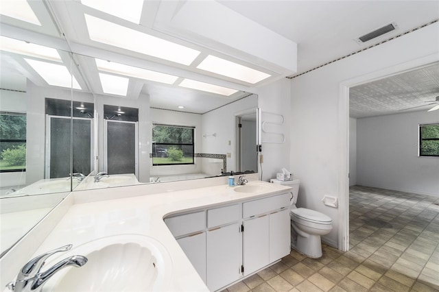 bathroom featuring vanity, toilet, ceiling fan, and a healthy amount of sunlight