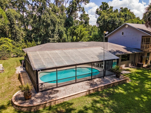 view of swimming pool with a lawn, glass enclosure, a patio area, and central AC unit