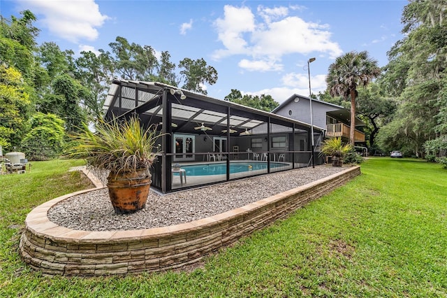 view of swimming pool with ceiling fan, a lanai, and a lawn