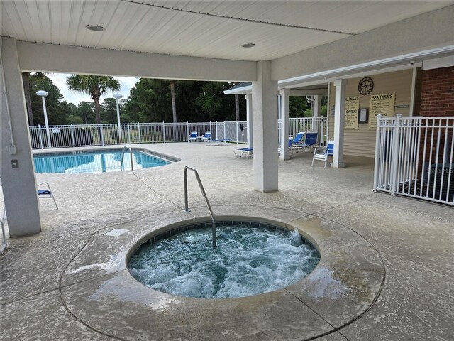 view of swimming pool featuring a hot tub and a patio area