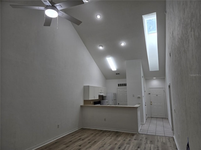 unfurnished living room with ceiling fan, high vaulted ceiling, and light wood-type flooring