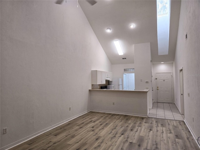 unfurnished living room with high vaulted ceiling and light hardwood / wood-style floors