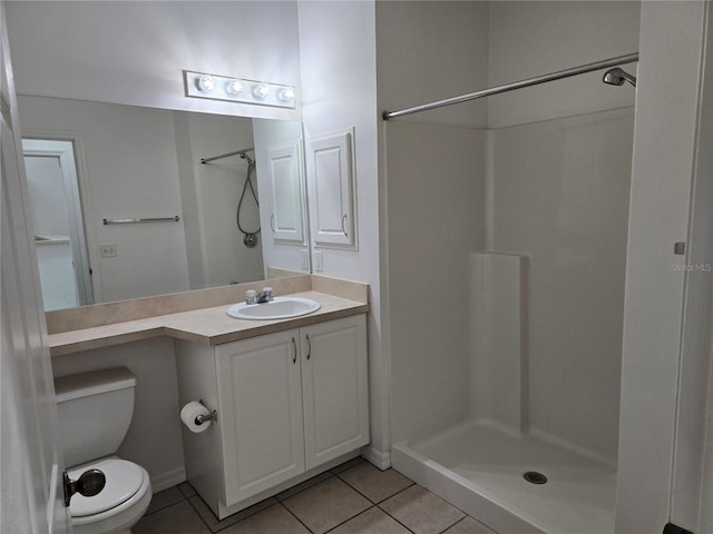 bathroom featuring tile patterned flooring, vanity, toilet, and walk in shower