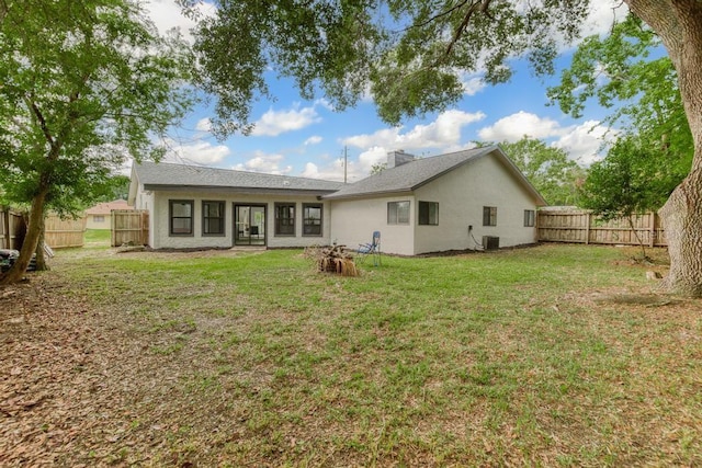 rear view of house with central AC unit and a lawn