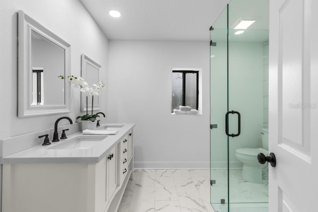 bathroom featuring vanity, a shower with shower door, and toilet