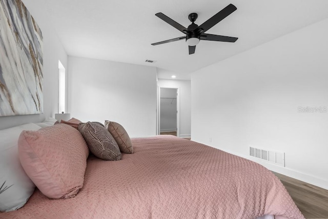 bedroom featuring wood-type flooring, a spacious closet, and ceiling fan