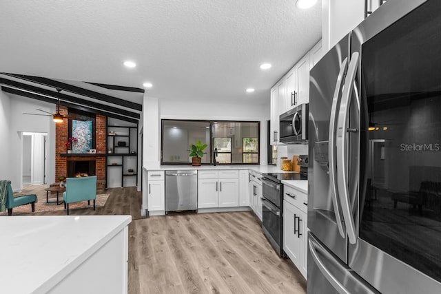 kitchen featuring a fireplace, light hardwood / wood-style flooring, white cabinets, and appliances with stainless steel finishes