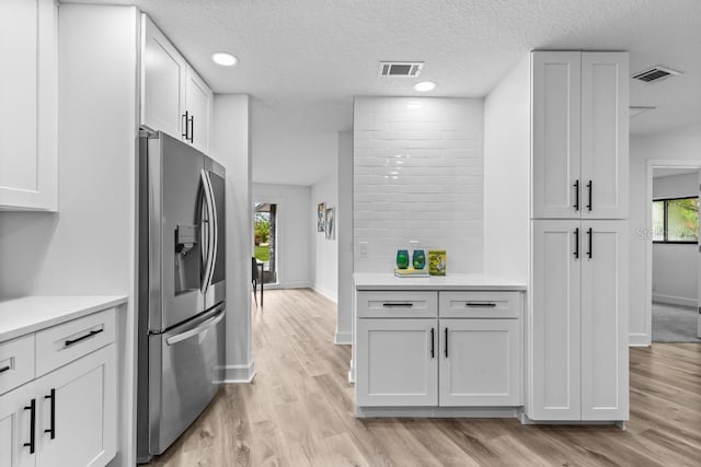 kitchen featuring light hardwood / wood-style floors, stainless steel fridge with ice dispenser, and white cabinets