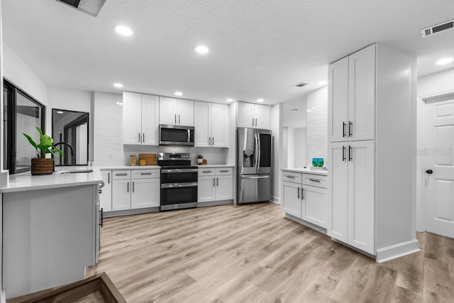 kitchen featuring white cabinetry, appliances with stainless steel finishes, and light wood-type flooring