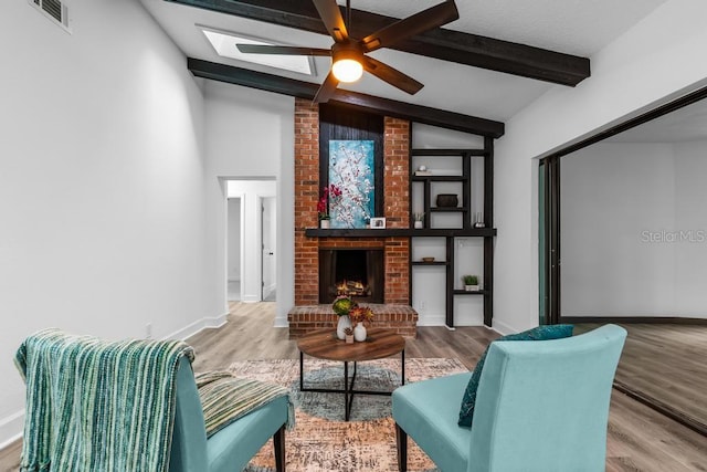 living room featuring a fireplace, lofted ceiling with skylight, and wood-type flooring