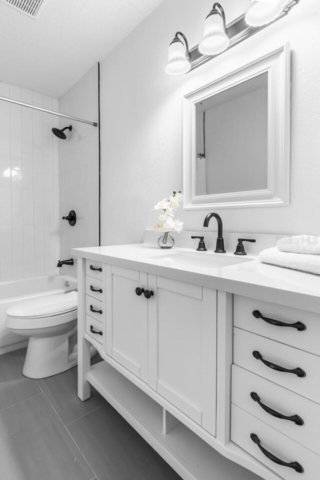 full bathroom featuring tiled shower / bath combo, vanity, and toilet